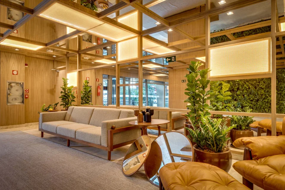 Espaço de convivência do Opus Penthouses, com sofás, madeira, plantas e luz natural.